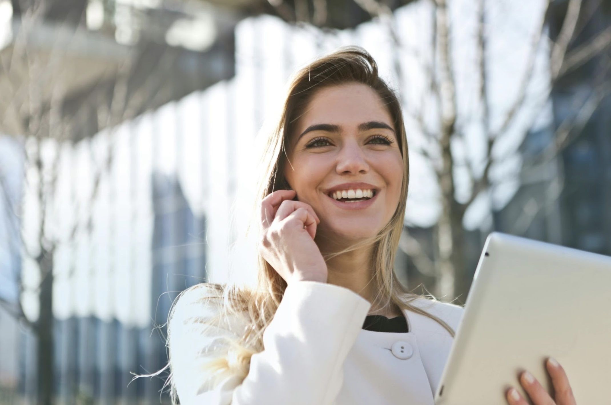 Smiling Woman Talking on Smartphone and Holding a Tablet